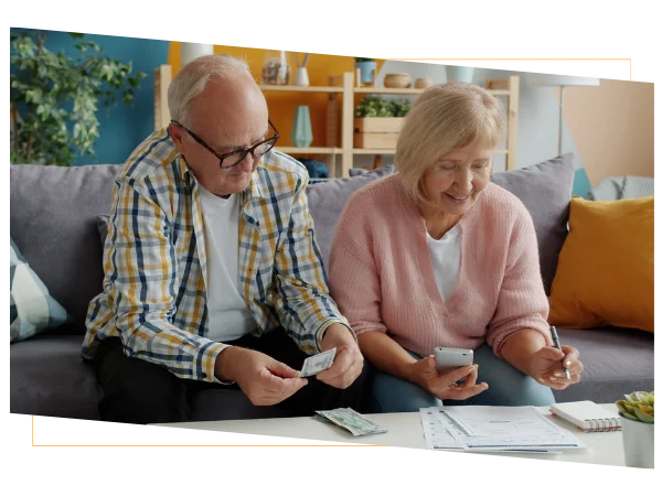 Elderly couple reviewing their finances at home on a couch, reflecting the guidance provided by health savings experts Elderly couple reviewing their finances at home on a couch, reflecting the guidance provided by health savings experts