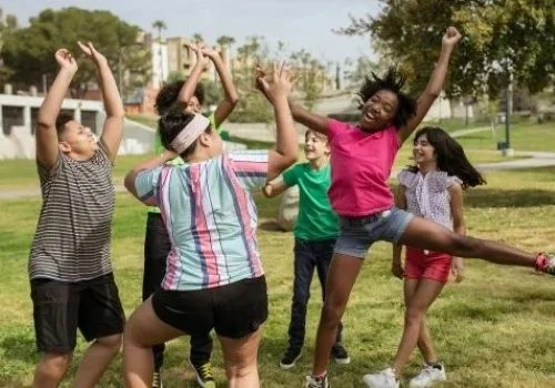 Diverse children playing outdoors together while sharing health insurance tips about staying active and healthy.